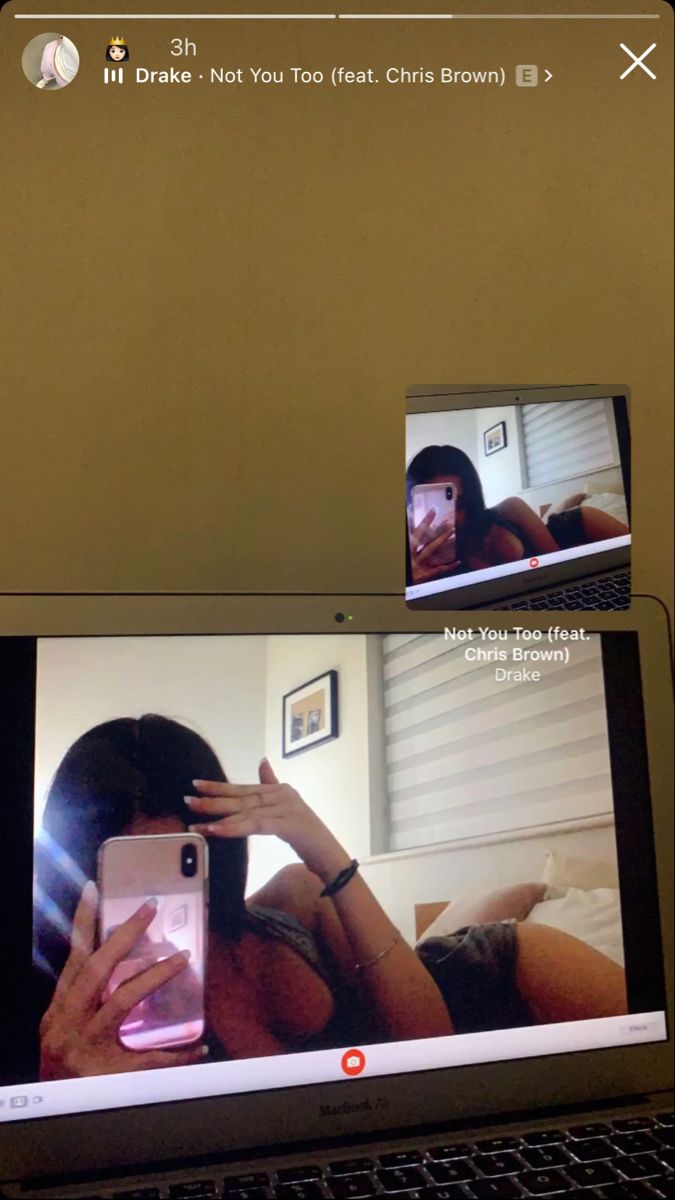 a laptop computer sitting on top of a desk with two people in the screen and one person holding a cell phone up to their ear