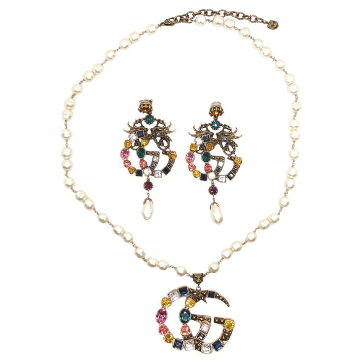 Elevate your style with the ultimate combination of elegance and luxury - the Gucci Multicolor Crystal Faux Pearl Logo Necklace & Earrings Set. This matching set is a statement in itself and a testament to your appreciation for high fashion and sophistication. This set provides the perfect coordination for a complete and glamorous look. The large gold tone 'GG' Gucci logos, embellished with multicolor crystals and faux pearls, are consistent across both the earrings and necklace, creating a harm Chanel Heels, Prada Dress, Pearl Logo, Logo Necklace, Fendi Handbag, Gg Logo, Necklace And Earrings Set, Necklace And Earrings, Necklace Earring Set