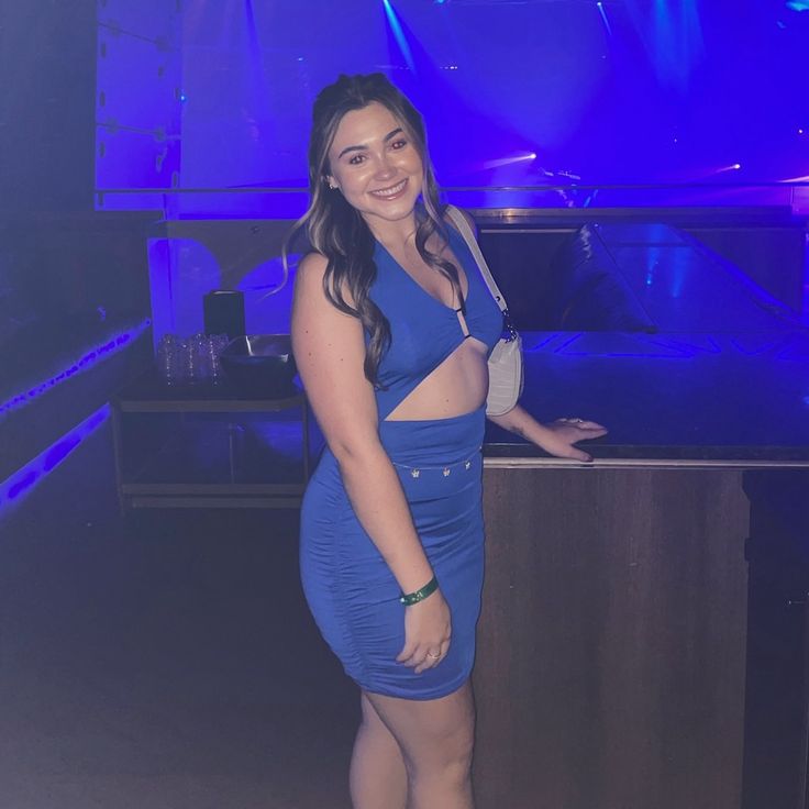 a woman standing in front of a counter with a blue light behind her and a piano on the other side