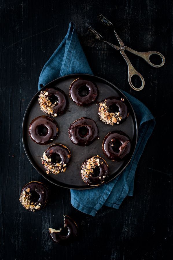 chocolate covered donuts with sprinkles on a plate next to a pair of scissors