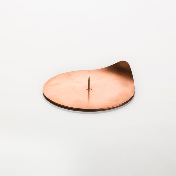 a clock made out of copper sitting on top of a white table next to a wall