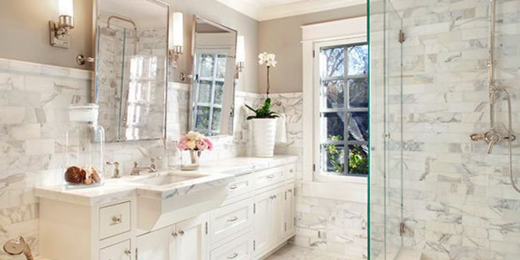 a large bathroom with marble walls and flooring is shown in this image, there are two sinks on either side of the bathtub