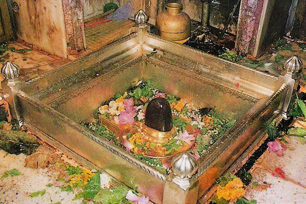 an ornate metal box with flowers and candles in it sitting on the floor next to other items