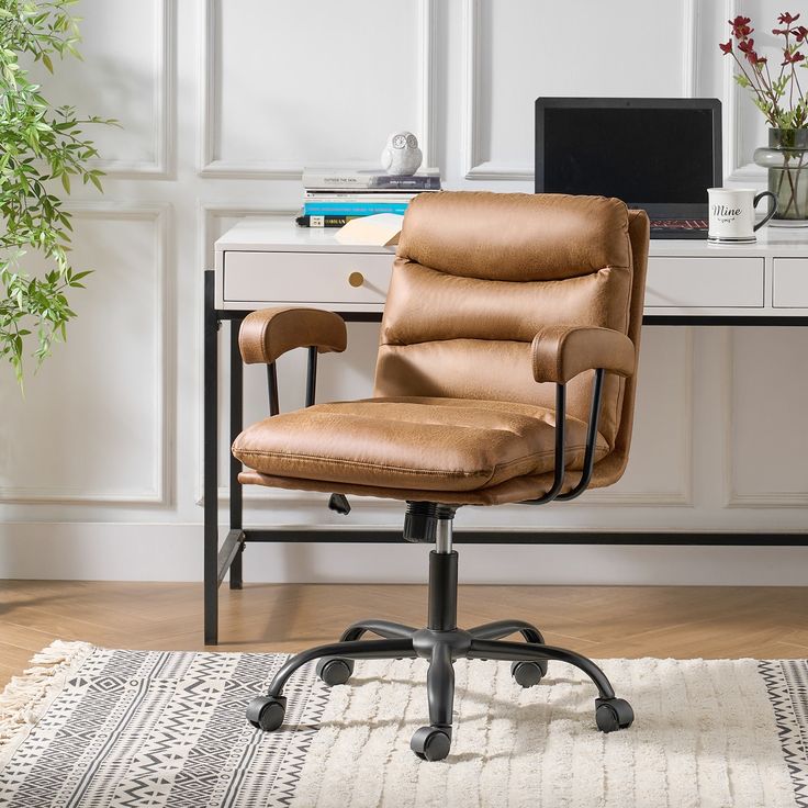 a brown leather office chair sitting in front of a desk with a laptop on it