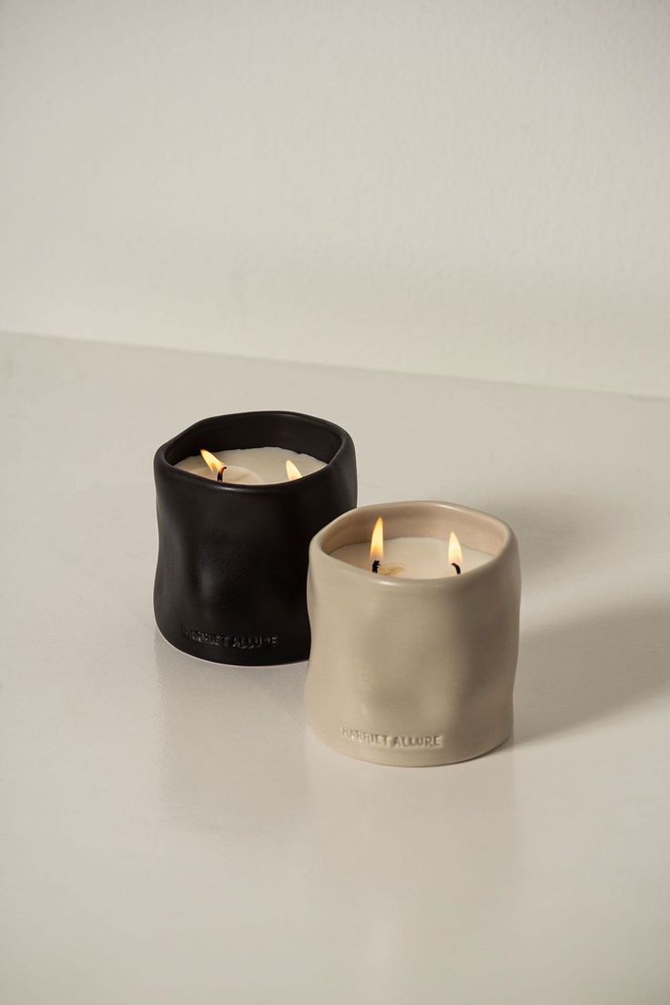 two candles sitting next to each other on top of a white table with one candle in the middle