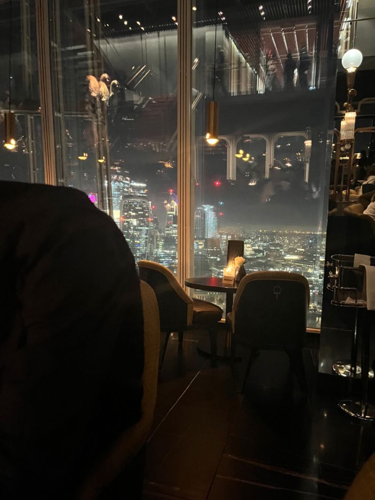 a view from the top of a skyscraper restaurant at night, looking down on city lights