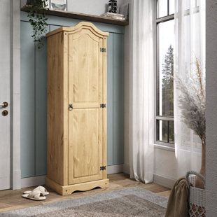 a tall wooden cabinet sitting in front of a window next to a rug and potted plant