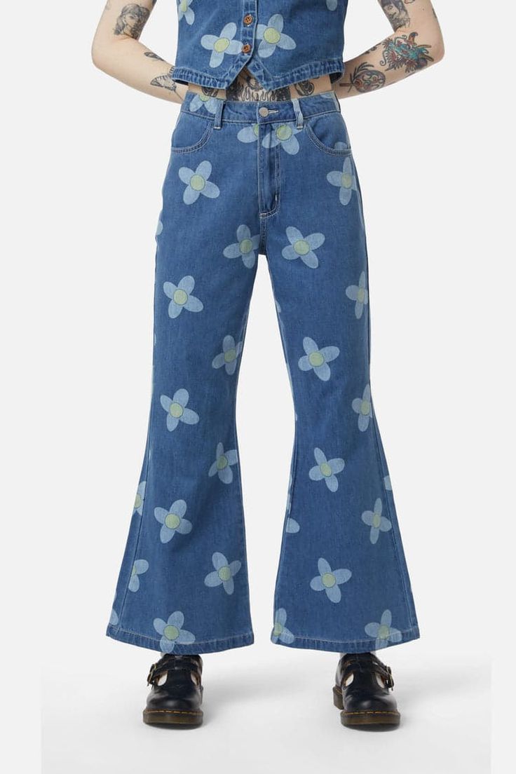 Step into the Daisy Do Jean, and let your legs bloom in a meadow of style. Unleash your inner flower child with flares that say goodbye to the mundane and hello to hippie chic. Clinging where they should with a fitted waistband and laying the foundation with a classic fly closure at the front, these are the pants that put the 'fun' in functional. Side pockets ensure your essentials are as close as daisies in a field, because what's a garden without a little practicality? And oh, the flared legs! Like petals reaching for the sun, they spread style and freedom with every move you make. Adorned with an all-over flower print, each step you take is a stride through a summer's day, all year round. Crafted from cotton denim, the Daisy Do Jean is your ticket to an eternal blossom festival. Kids Scrubs, Raincoat Kids, The Mundane, Leggings Kids, Scrub Pants, Hippie Chic, Flower Child, Flower Print, Flare Pants