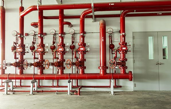 red pipes and valves are lined up against the wall