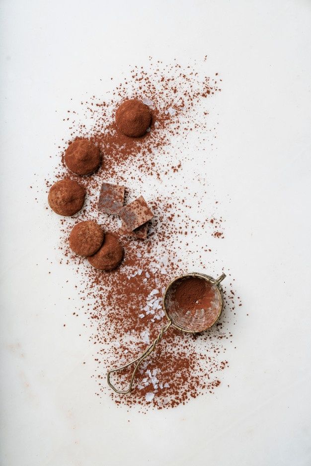 chocolate truffles and powdered sugar on a white surface