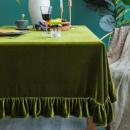 a green table cloth with ruffled edges on a wooden chair in front of a potted plant