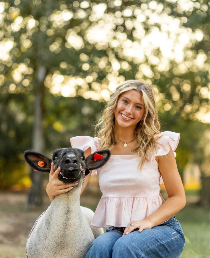 a woman kneeling down next to a sheep