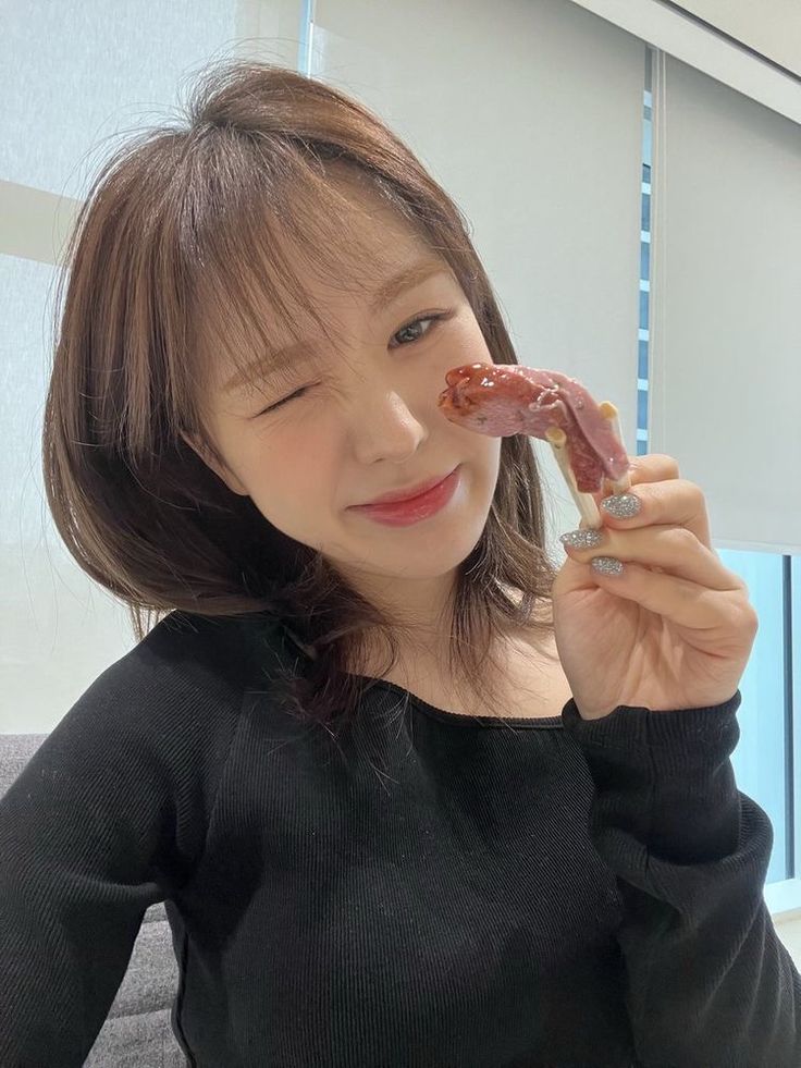 a young woman holding up a piece of food to her face