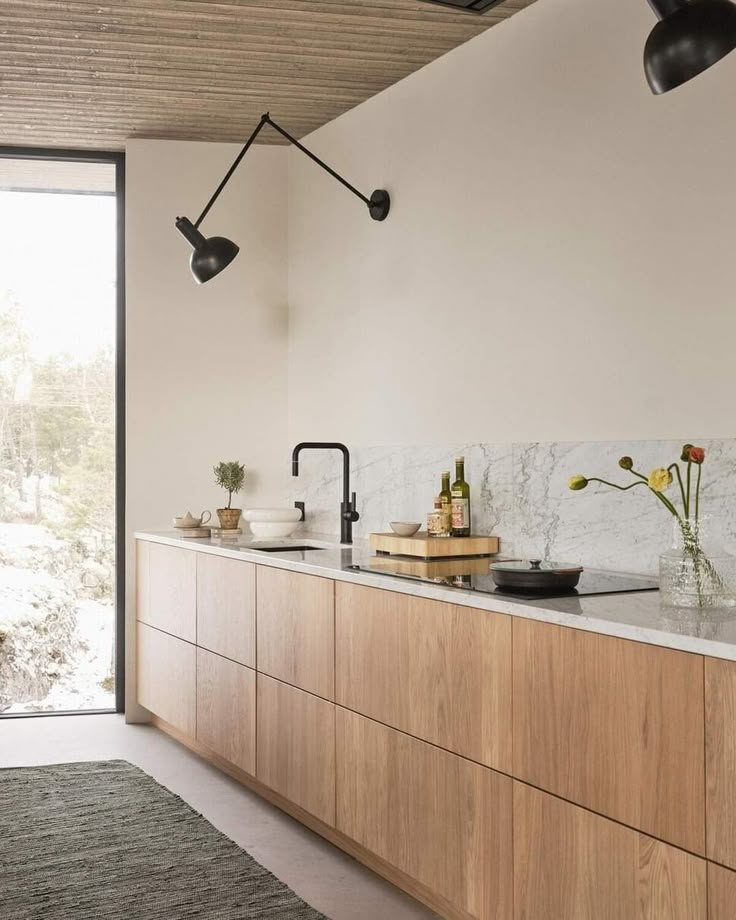 a kitchen with marble counter tops and wooden cabinets, along with black pendant lights hanging from the ceiling