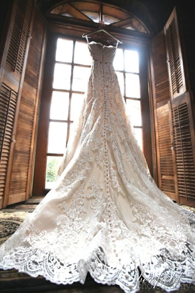 a wedding dress hanging in front of a window