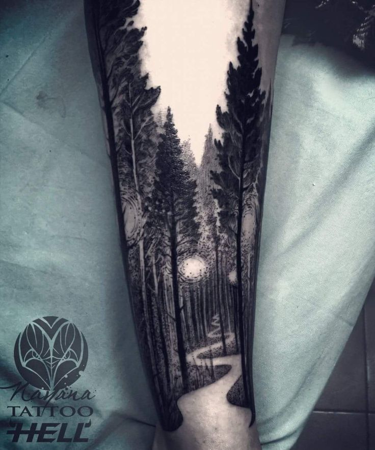 a man's arm with a black and white forest scene tattoo on the forearm