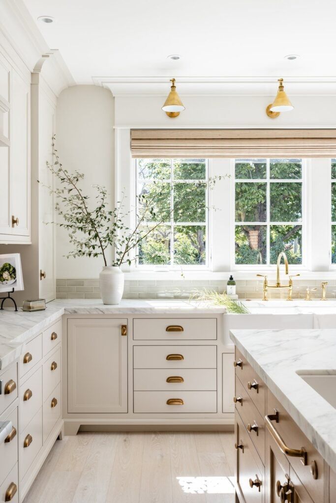 a kitchen with white cabinets and gold pulls on the handles, counter tops and drawers