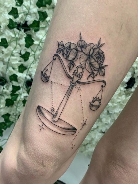 a tattoo on the leg of a woman with a scale and flowers in it,