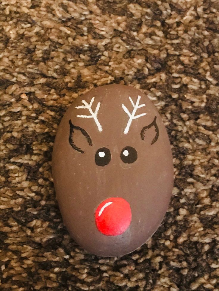 a painted rock with reindeer's nose and antlers on it sitting on the ground