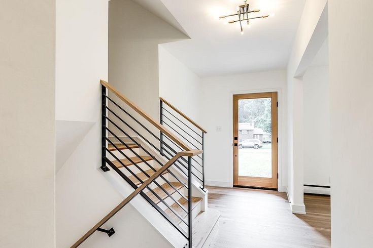 an empty room with stairs and wooden floors in the center, along with a door leading to another room