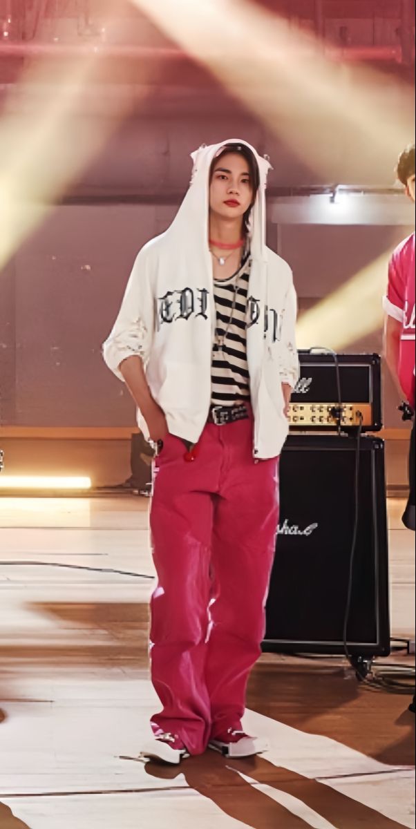 a man standing on top of a stage wearing pink pants and a white hoodie