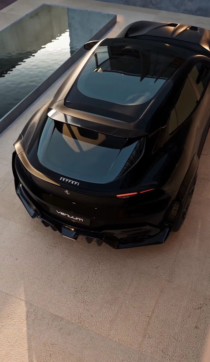 a black sports car parked on the side of a road next to a body of water