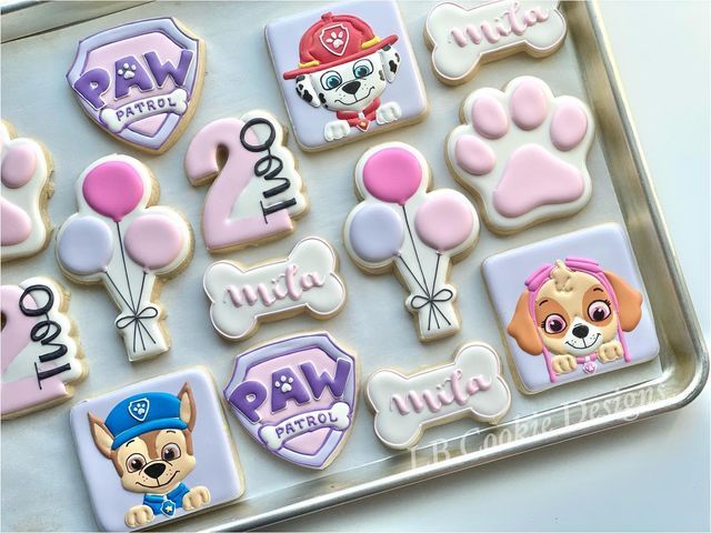 decorated cookies in the shape of dogs and paw patrol on a cookie sheet with pink icing