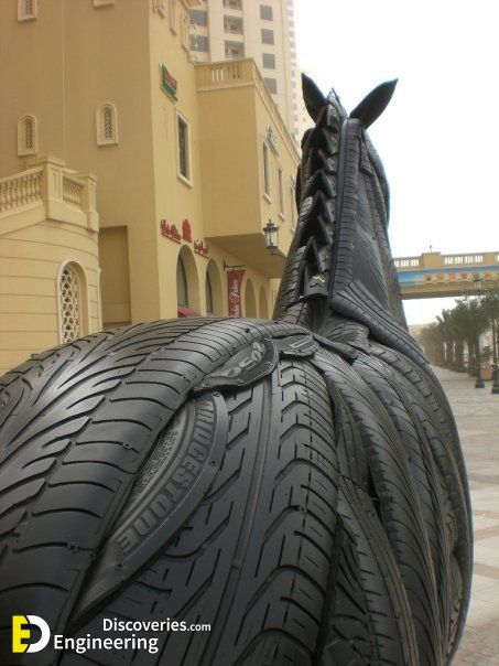 a sculpture of a horse's head made out of tires in front of a building