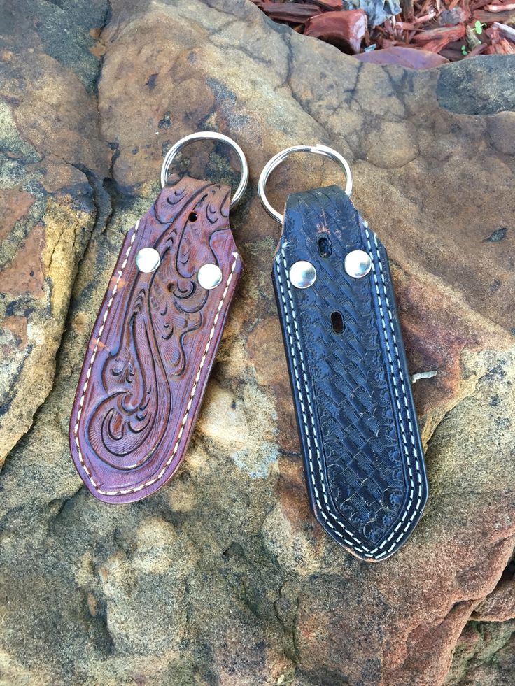 two leather key chains sitting on top of a rock