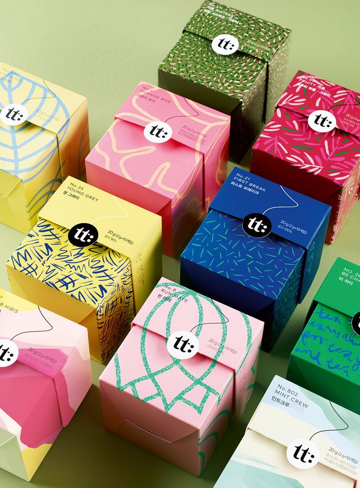 many colorful boxes with tags on them sitting next to each other in front of a green background