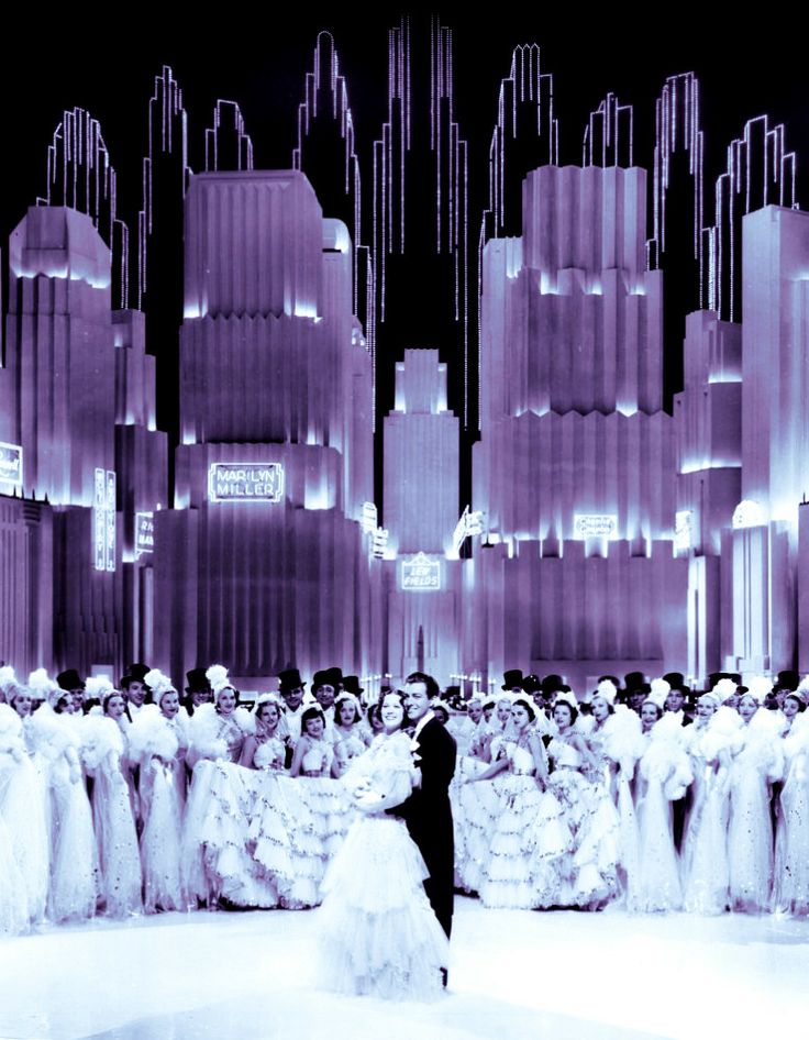 a man and woman standing in front of a large group of people wearing gowns