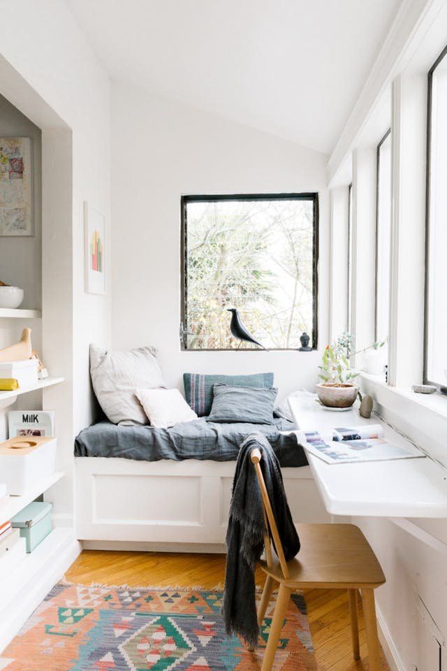 a window seat in the corner of a room with a rug on the floor next to it