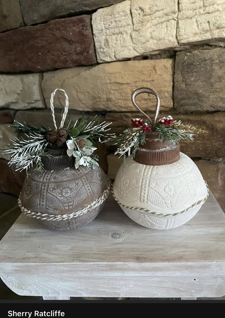 two white vases sitting on top of a wooden table next to a stone wall