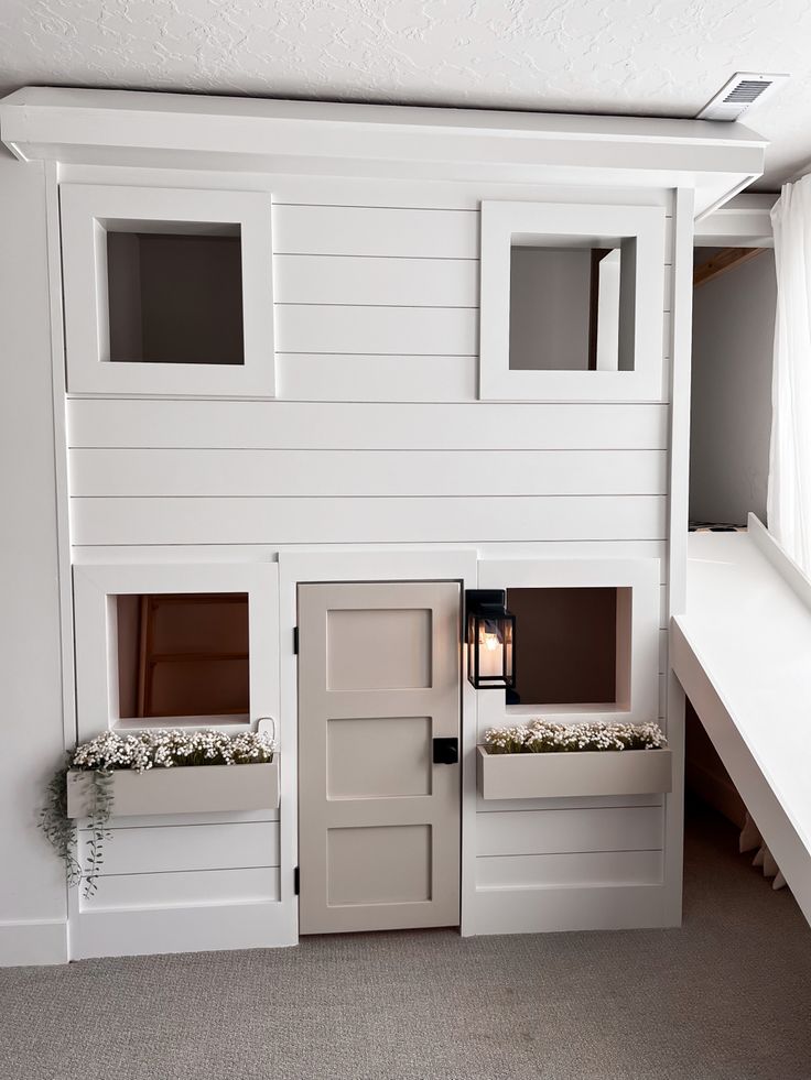 a white bunk bed with two windows and a window seat on the bottom level is built into the wall