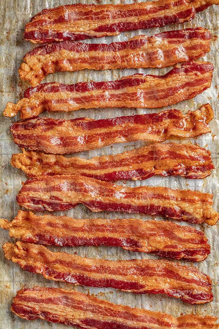 bacon strips are lined up on a baking sheet