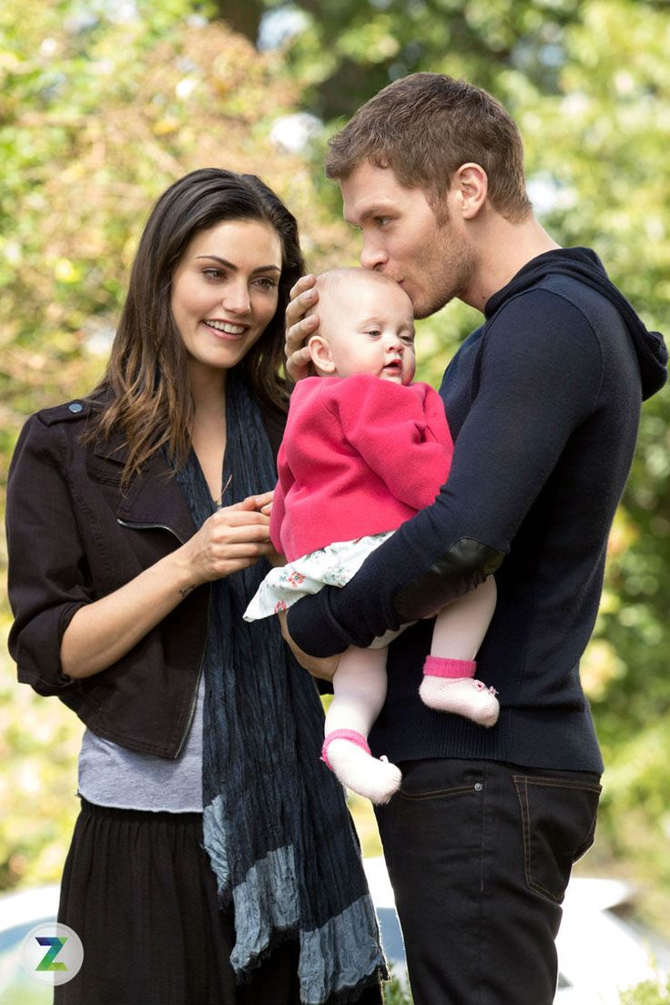 a man and woman holding a baby in their arms while standing next to each other