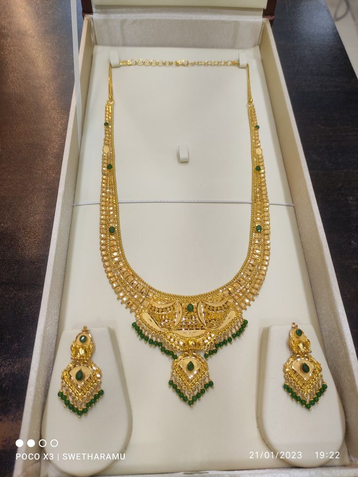 an elaborate necklace and matching earrings in a white box with gold trimmings on it