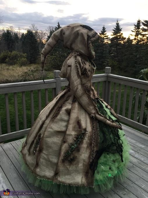 a woman wearing a dress made out of fabric and green tulle on a deck