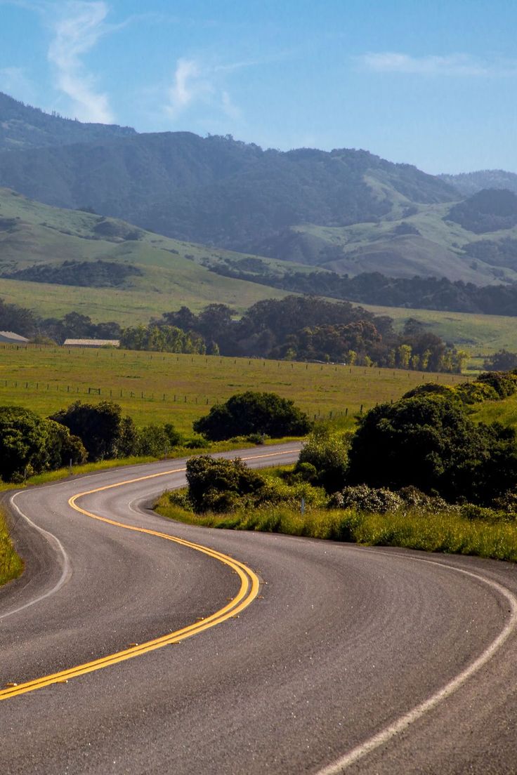 a curved road with mountains in the background