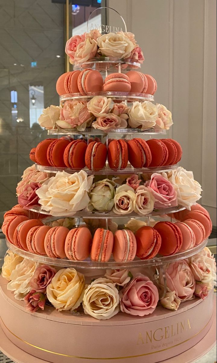 a pink cake with macaroons and flowers on it's tiered display