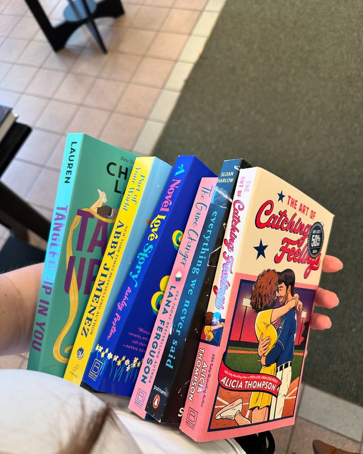 a person holding a row of books in their hand