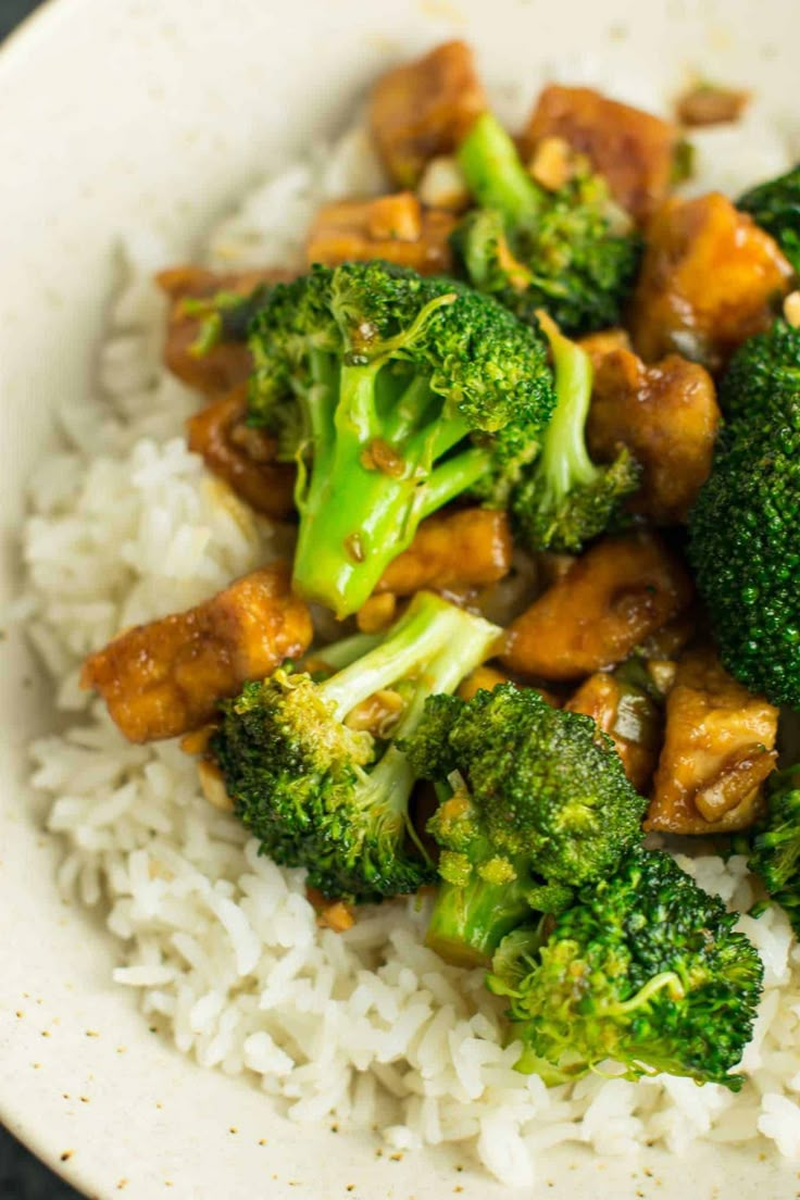 a bowl filled with rice and broccoli covered in sauce