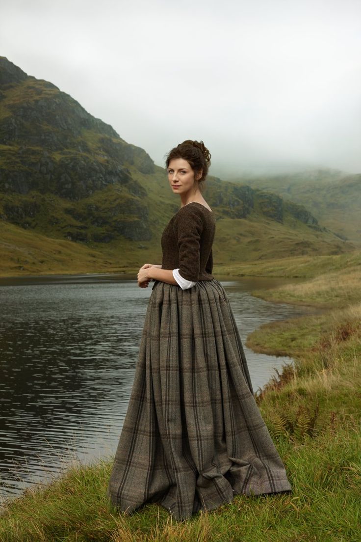 a woman in a long dress standing by the water