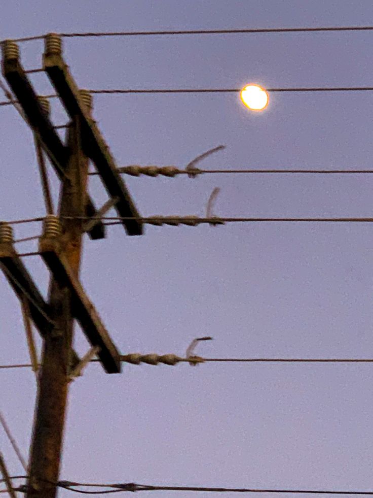 the full moon is seen through power lines