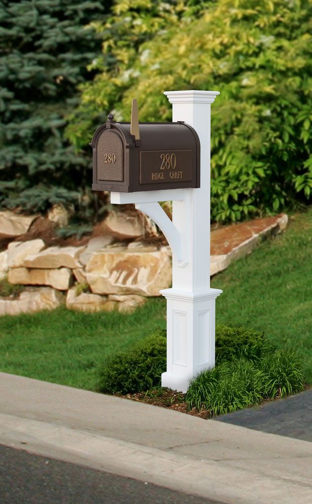 a mailbox in the middle of a lawn with rocks and grass behind it,