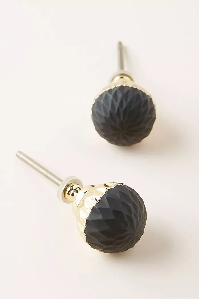 the black and gold earrings are on display in front of a white background with silver ear pins