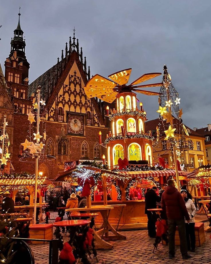 people are standing in front of an elaborately decorated christmas village at night time with lights and decorations