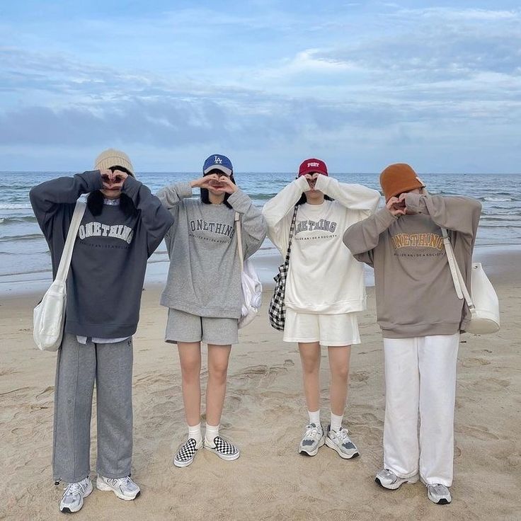 three people standing on the beach with their hands behind their heads and covering their eyes