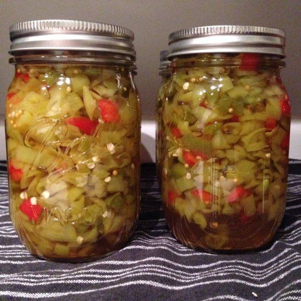 two jars filled with pickled vegetables sitting on a table