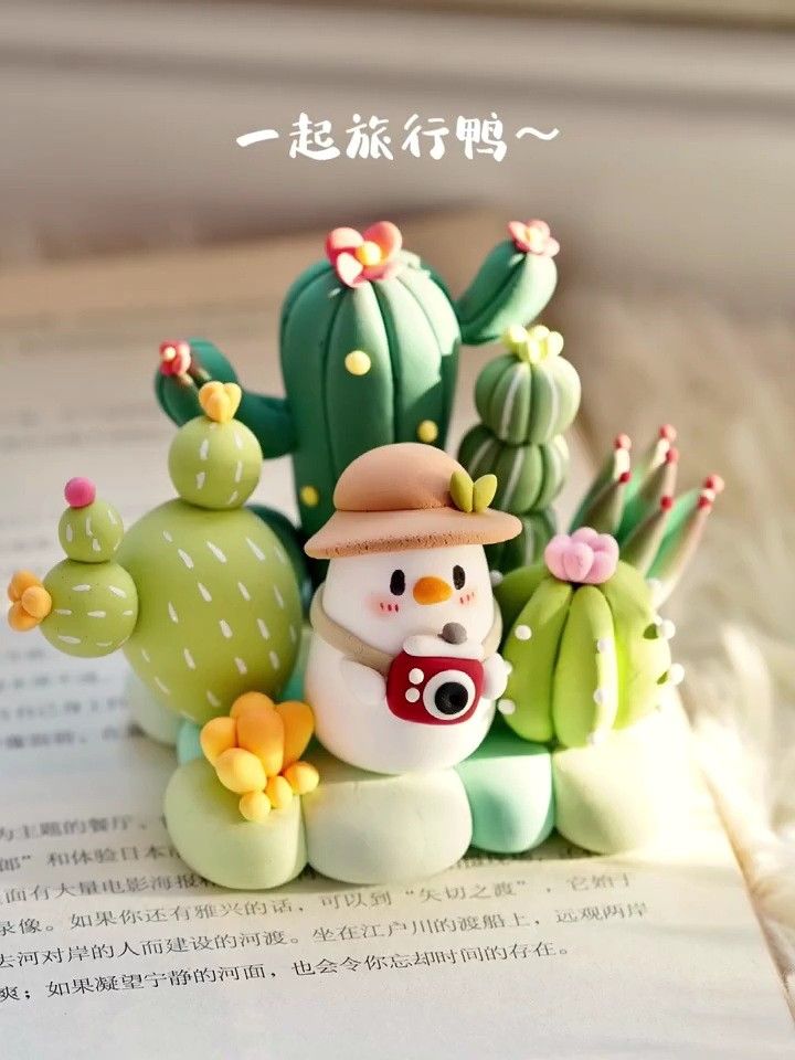 a small toy snowman sitting on top of a book next to cacti